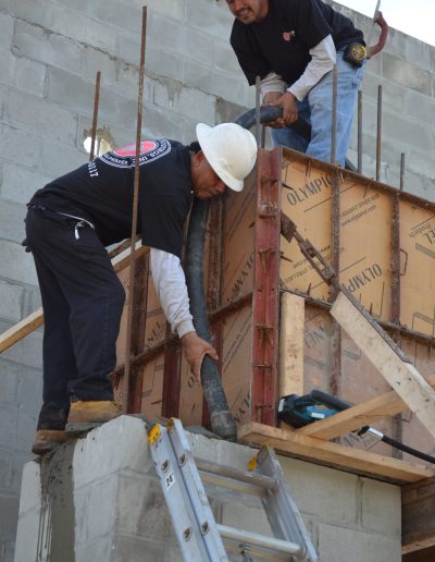 two workers stand on scaffolding as they work on a project