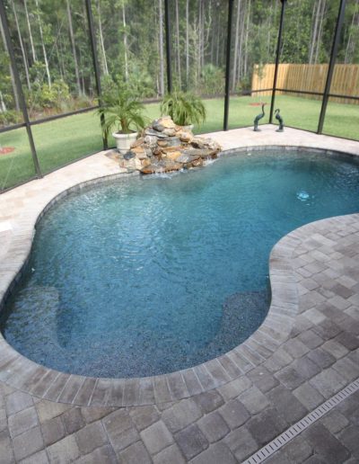 pool deck with a rock waterfall formation