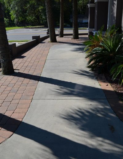 a sidewalk surrounded by brick pavers with landscaping