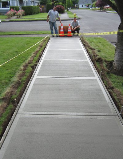 two men look at a freshly poured sidewalk