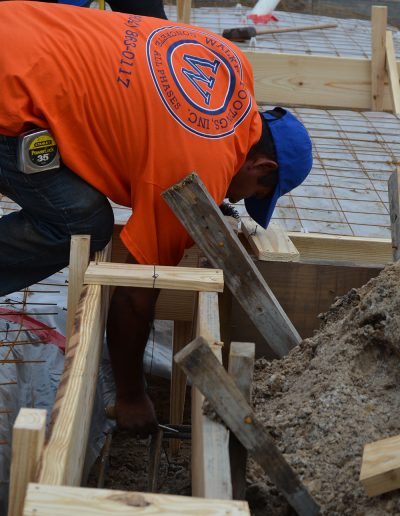 a worker reaches down to work on a concrete footer