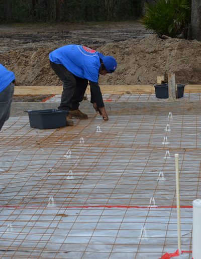 three men bend over while working on a concrete footing