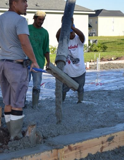 three workers pour concrete at a project