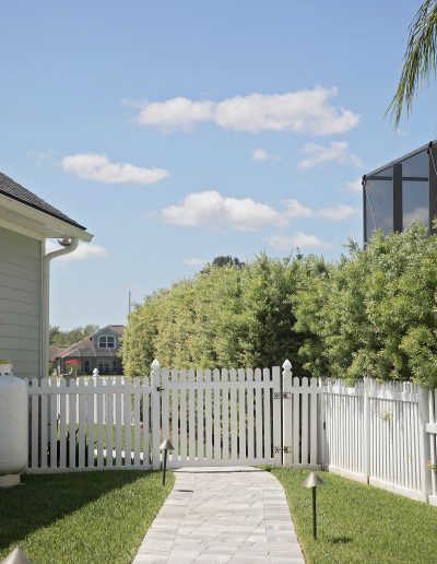 a sidewalk created by Walker Footings runs beside a house to a white picket fence