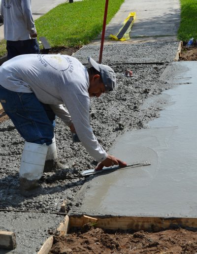 a worker smoothing a newly poured driveway