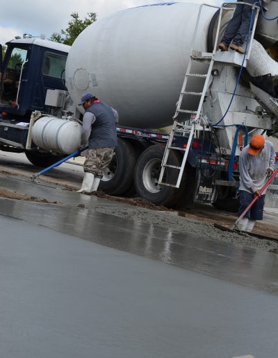 a worker smooths out fresh concrete by a cement truck